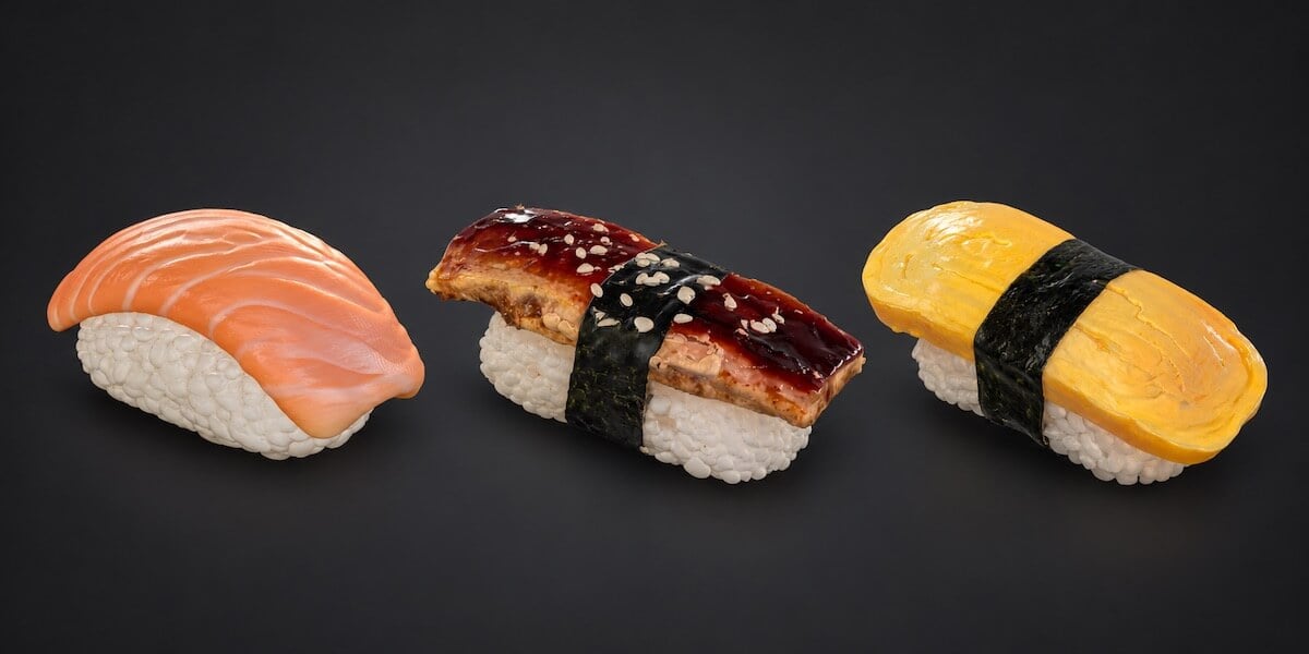 Salmon, eel and tamago nigiri 3D models displayed side by side on a dark background.